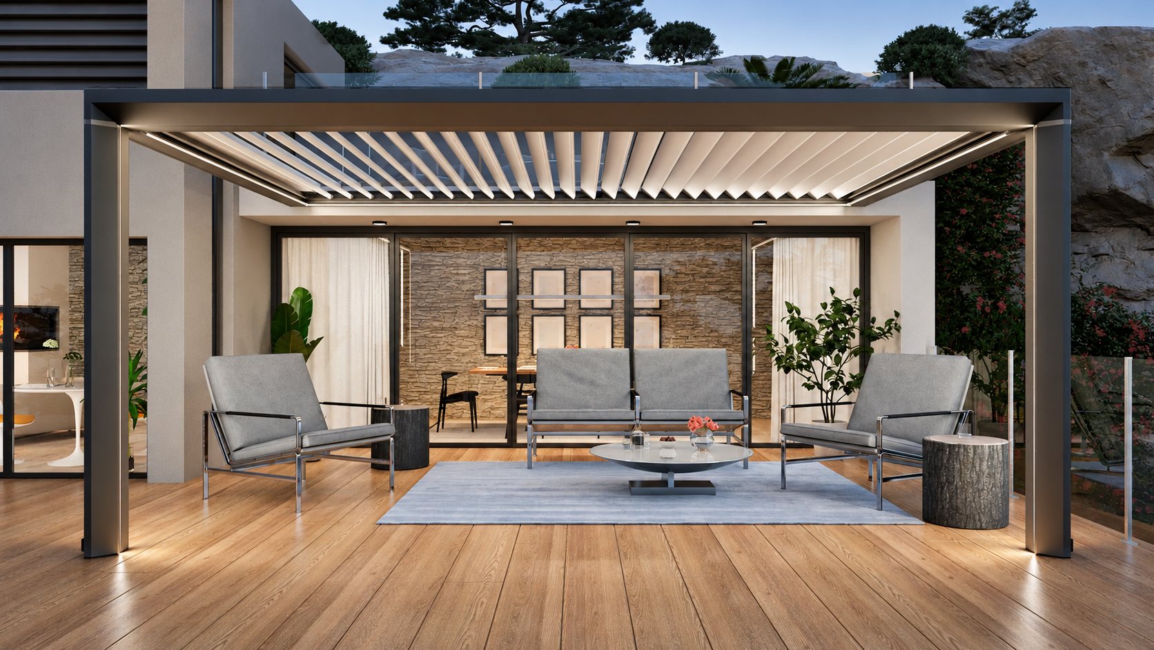 Pergola moderne à lames orientables éclairée au crépuscule, abritant un salon de jardin gris avec table basse sur une terrasse en bois devant une maison.